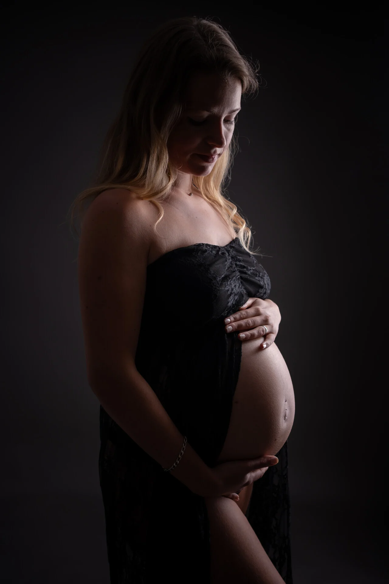 Future maman en robe noire, lumière artistique en contre-jour – séance grossesse en studio près de Rouen