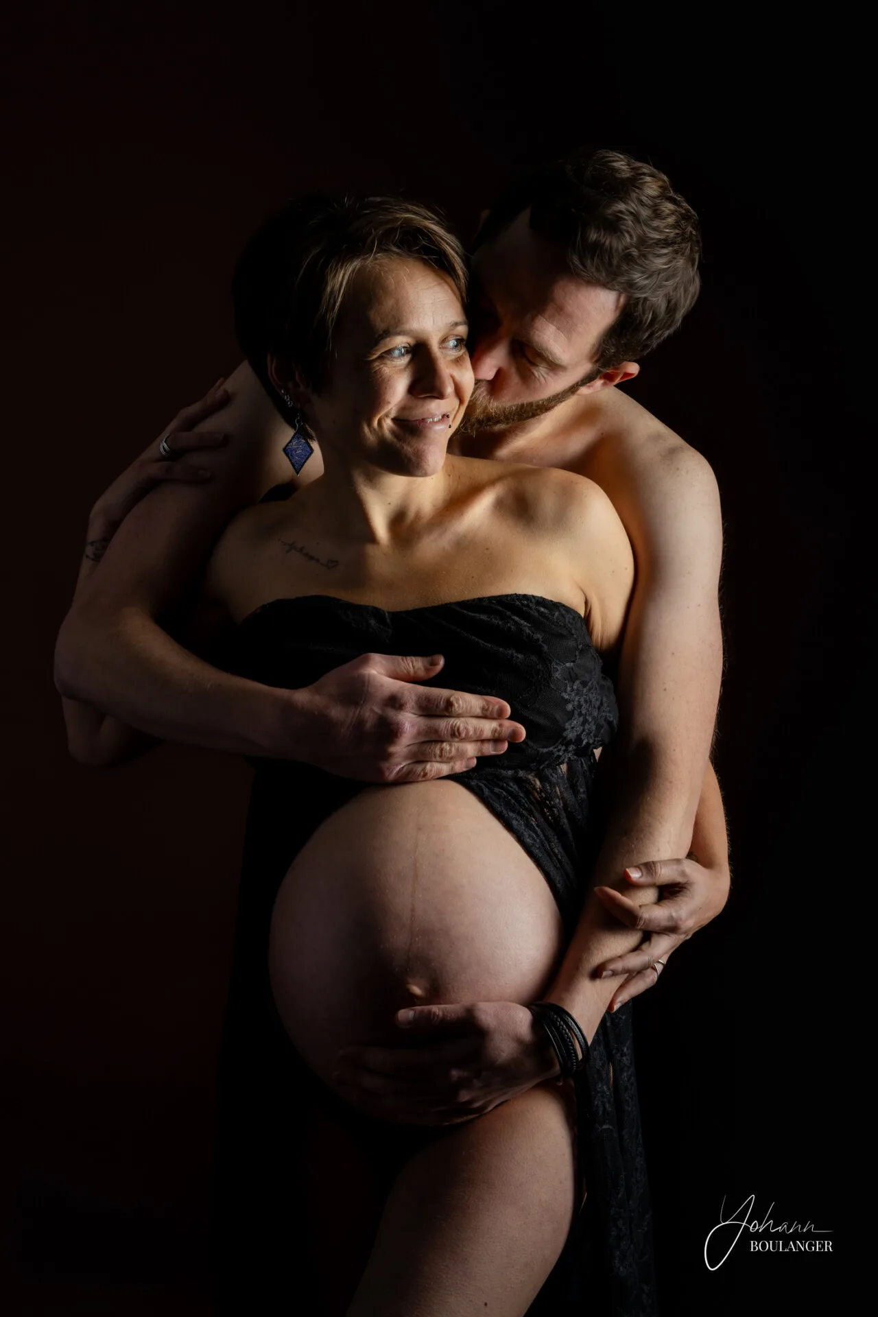Couple enlacé en séance photo grossesse, ventre rond mis en valeur