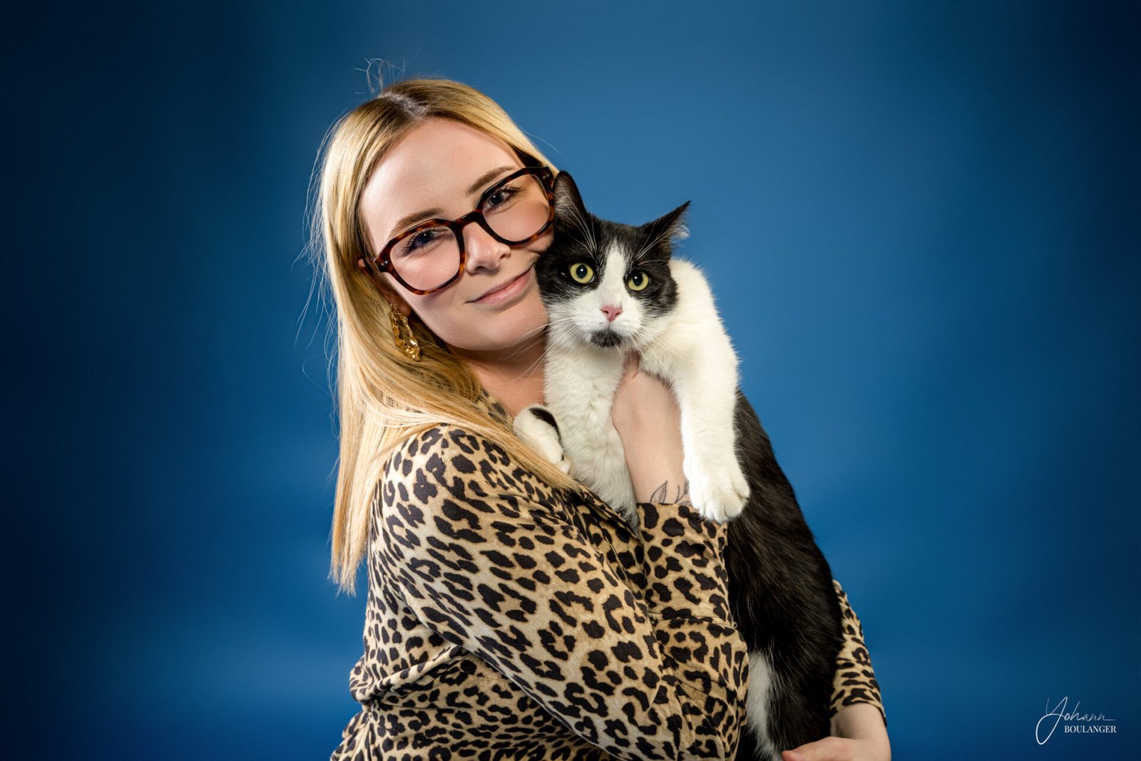 Portrait studio d’un chat noir et blanc aux grands yeux jaunes avec sa maitresse – photo animalière professionnelle à Elbeuf, Rouen, Bourgtheroulde
