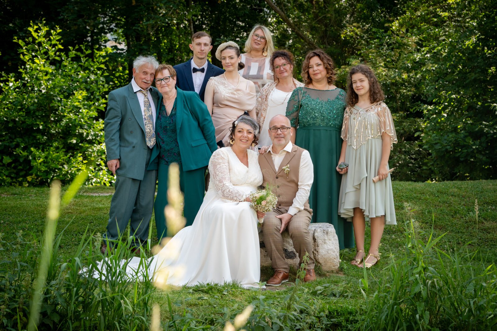 Photo de famille en extérieur, parents et enfants assis dans l’herbe en pleine nature