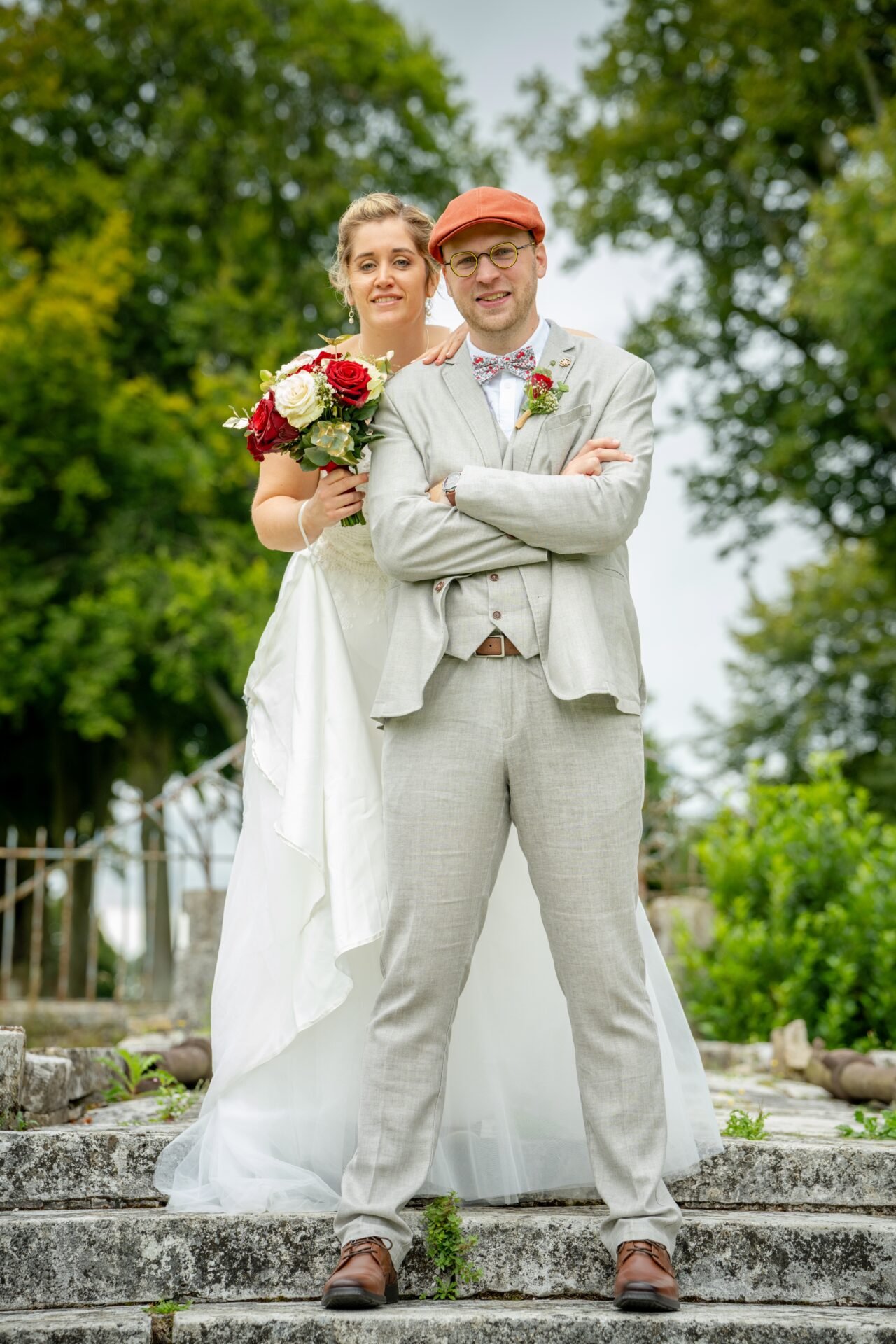 Photographe de Mariage Normandie - Immortalisez le plus beau jour de votre vie en photos ! 1 Couple de mariés souriant, l’homme portant une casquette, dans un décor extérieur