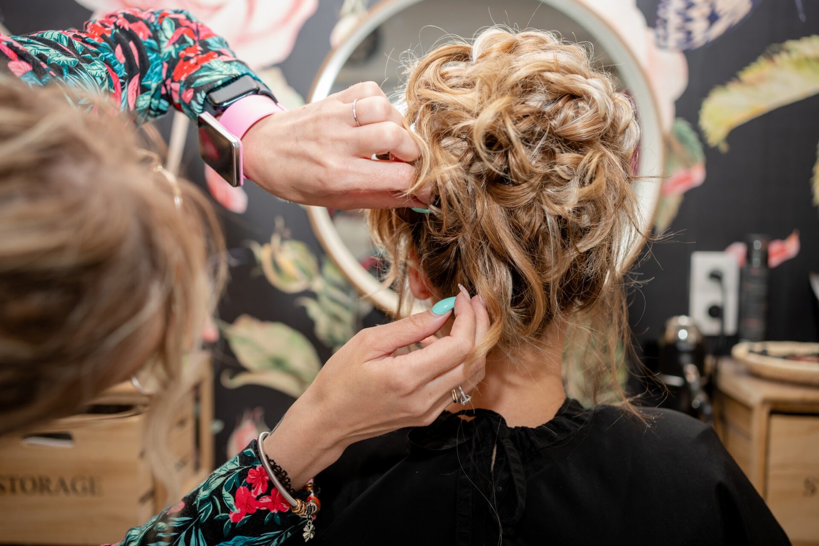 Coiffeuse réalisant un chignon sophistiqué pour une mariée, préparation en salon le jour du mariage.