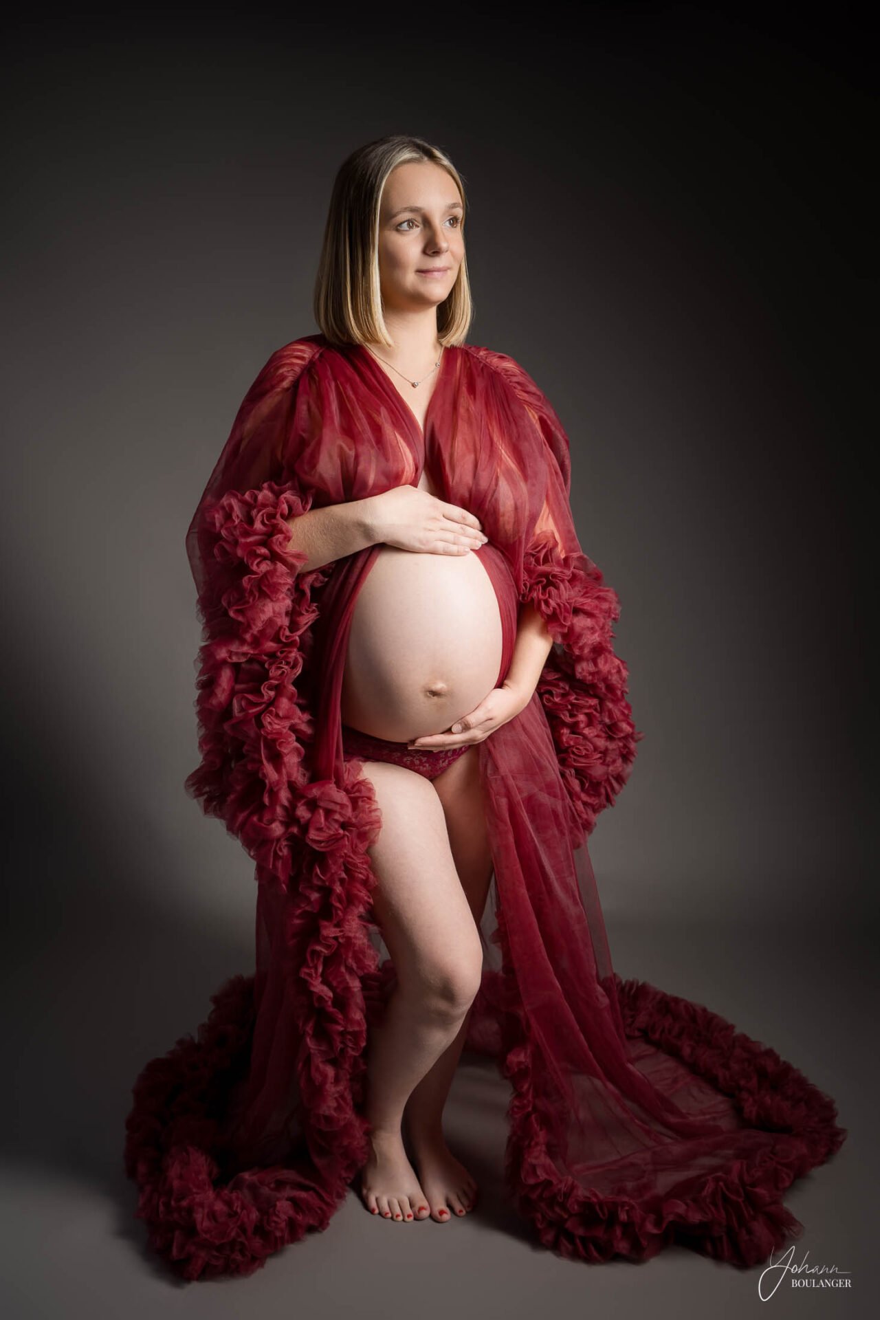 Séance photo grossesse en studio par Yohann Boulanger Photographe à Grand Bourgtheroulde, proche Rouen, Elbeuf, Bourg-Achard et Le Neubourg, future maman portant robe en tulle rouge.