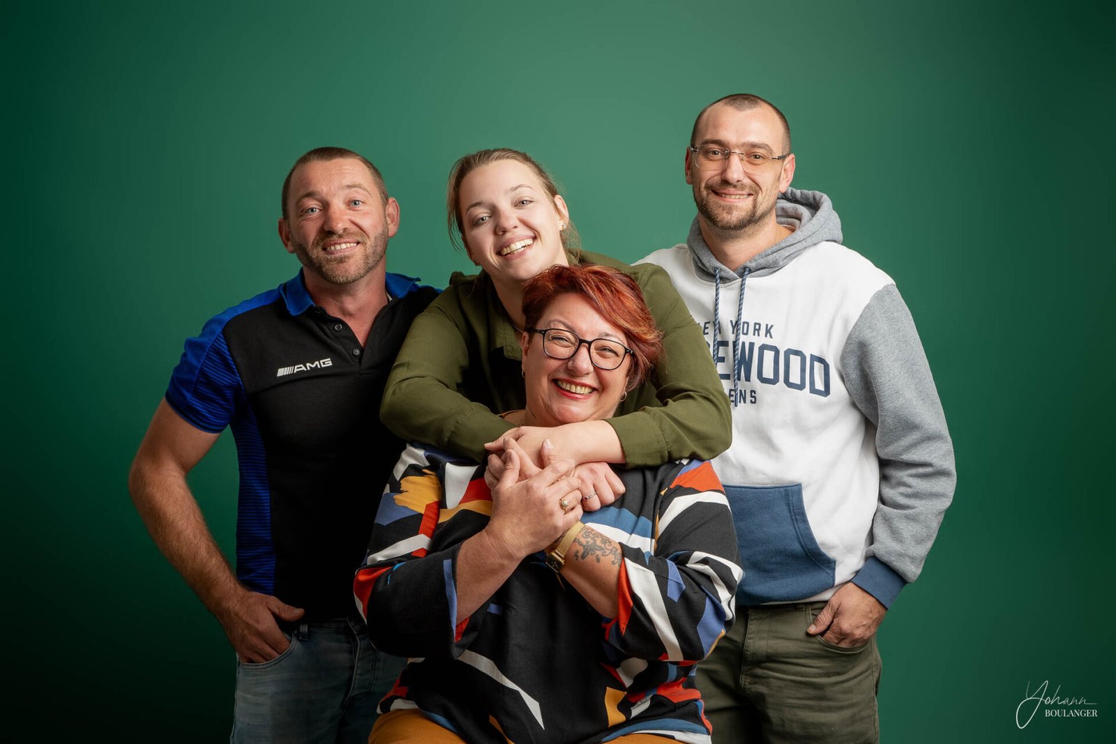 Portrait de famille souriante avec enfant sur tabouret, séance photo studio Rouen